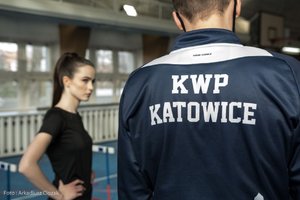 Zdjęcie kolorowe. Widoczna Miss Polski 2020 oraz plecy policjanta z bluza z napisem KWP Katowice na terenie hali sportowej. Autor zdjęcia: Arkadiusz Ciozak