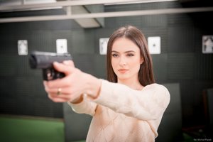 Zdjęcie kolorowe. Widoczna Miss Polski 2020 celująca z pistoletu. Autor zdjęcia: Michał Piątek