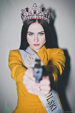 Zdjęcie kolorowe. Widoczna Miss Polski 2020 trzymająca w dłoniach pistolet. Autor zdjęcia: Michał Piątek