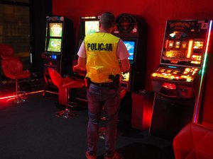 Policjant stojący tyłem w salonie gier hazardowych i cztery automaty do gier