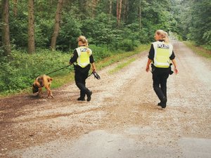 Zdjęcie kolorowe. Widoczne umundurowane policjantki niemieckie wraz z psem służbowym