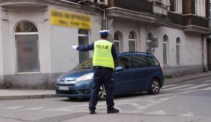 Kolorowa fotografia przedstawia policjanta wydziału ruchu drogowego kierującego ruchem.