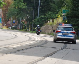Kolorowa fotografia przedstawia radiowóz i motocykl policyjny.