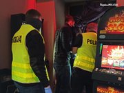 Zdjęcie kolorowe. Policjanci oraz inne służby obok autoamtów do gier hazardowych