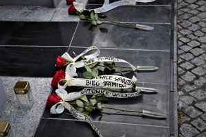 Kolorowa fotografia. Widoczne czerwone róże, które złożyli pod pomnikiem uczestnicy biegu.
