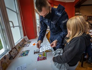 Policjant z dzieckiem oglądają kartki.