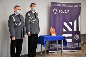 Umundurowani przedstawiciele kadry kierowniczej, w tle baner z napisem Policja.