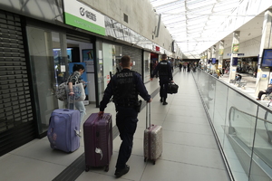 policjancie w holu dworca przemieszczają się z walizkami należącymi do kobiety idącej obok policjantów