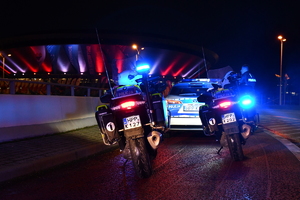 Dwa policyjne motocykle i radiowóz na tle oświetlonego Spodka.