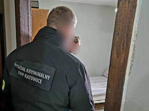 zdjęcie przedstawia policjanta wykonującego czynności z zatrzymanym wewnątrz budynku