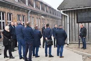 Policjanci podczas spotkania seminaryjnego w Auschwitz. Przewodnik i osoby skierowane w jego stronę.