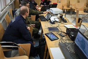 Zdjęcie. Widoczni policjanci i inne osoby przy komputerach w pomieszczeniu