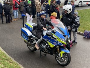 Na zdjęciu widoczny policjant oraz uczestniczka wydarzenia siedząca na policyjnym motocyklu