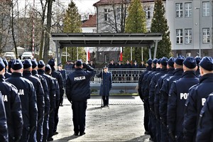 zdjęcie przedstawia stojących nowych policjantów i zastępcę komendanta wojewódzkiego oddającego honor