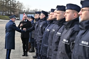 zdjęcie przedstawia policjantów stojących w szeregu, zastępca komendanta gratuluje podając rękę