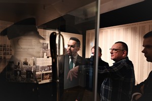 zdjęcie przedstawia mężczyzn oglądających eksponat w szklanej gablotce