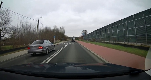 Na zdjęciu widzimy szybę czołową od wewnątrz pojazdu. Przez szybę, z lewej strony, widać srebrny pojazd przed przejściem dla pieszych.