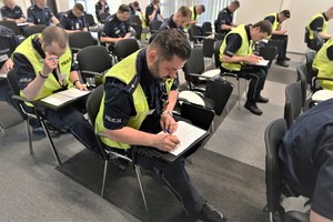 Zdjęcie. Grupa umundurowanych policjantów na sali podczas testu wiedzy
