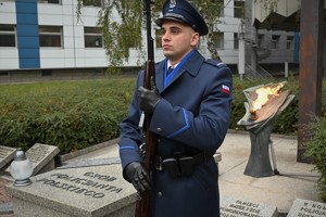 Zdjęcie. Warta honorowa umundurowanego policjanta z bronią długą przed Grobem Policjanta Polskiego