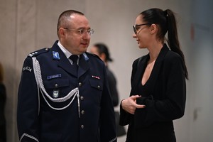 Zdjęcie przedstawia stojącego policjanta oraz kobietę