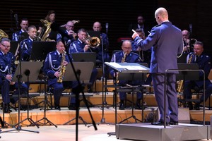 Zdjęcie przedstawia dyrygenta i orkiestrę.