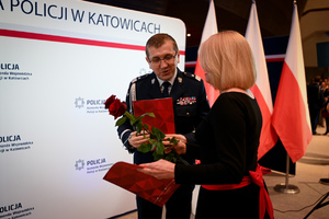 Zdjęcie przedstawia policjanta oraz kobietę trzymającą róże