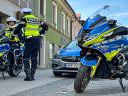 dwaj umundurowani policjanci przy dwóch oznakowanych motocyklach oraz radiowozie policji