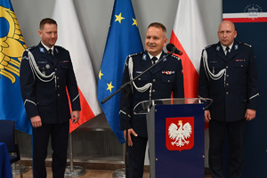 Pierwszy Zastępca Komendanta Wojewódzkiego Policji w Katowicach stoi przy mównicy, obok stoją dwaj Zastępcy Komendanta Wojewódzkiego Policji w Katowicach