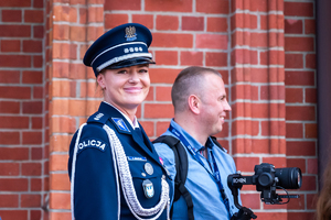 kolorowe zdjęcie przestawiające uśmiechniętą policjantkę oraz osobę cywilną z aparatem fotograficznym
