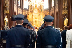 kolorowe zdjęcie przedstawiające policjantów kompani honorowej stojących wewnątrz bazyliki. Zdjęcie wykonane za ich plecami.