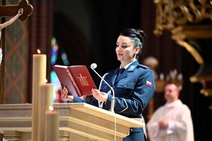 policjantka stojąca na mównicy bazyliki trzymająca w ręku terminarz mszalny
