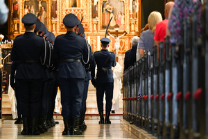 kolorowe zdjęcie policjantów kompani honorowej trzymających szable. Zdjęcie wykonane za ich plecami.