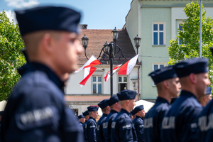 Kolorowe zdjęcie policjantów, w tle flagi RP