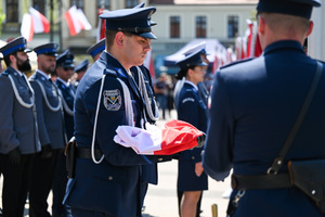 kolorowe zdjęcie policjanta Kompani Honorowej trzymający flagę RP