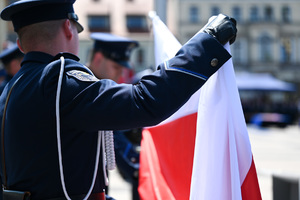 kolorowe zdjęcie policjanta trzymającego flagę RP