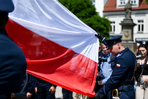 kolorowe zdjęcie policjanta trzymającego flagę RP