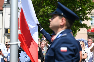 kolorowe zdjęcie policjanta trzymającego flagę RP