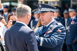 kolorowe zdjęcie przedstawiające zastępcę Komendanta Głównego Policji nadinsp. Rafała Kochańczyka stojącego naprzeciw mężczyzny ubranego w ciemny garnitur
