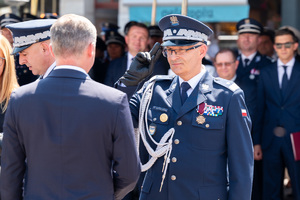 Komendant Wojewódzki Policji nadinsp. Mariusz Krzystyniak oddaje honor mężczyźnie w garniturze