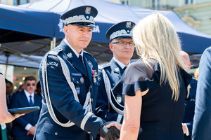Generałowie policji podchodzą do kobiety, jeden z nich ściska jej dłoń