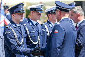 kolorowe zdjęcie przedstawiające policjanta korpusu oficerów starszych oraz policjantów korpusu podoficerów