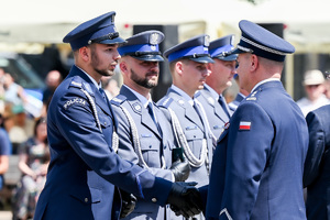 kolorowe zdjęcie przedstawiające policjanta korpusu oficerów starszych oraz policjantów korpusu podoficerów