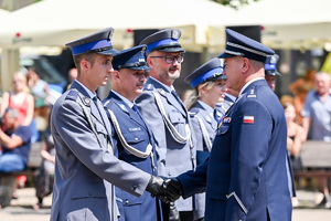 kolorowe zdjęcie przedstawiające policjanta korpusu Oficerów Starszych gratulującego policjantom