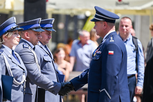 kolorowe zdjęcie przedstawiające policjanta korpusu Oficerów Starszych gratulującego policjantom