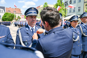 kolorowe zdjęcie przedstawiające mężczyznę w garniturze odznaczającego Oficera Policji