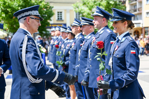 kolorowe zdjęcie przedstawiające Generała Policji wręczającego róże policjantce, stojącej w szeregu z policjantami