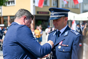 kolorowe zdjęcie przedstawiające mężczyznę w garniturze odznaczającego policjanta Korpusu Oficerów Starszych
