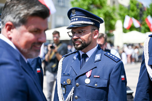 kolorowe zdjęcie przedstawiające mężczyznę w garniturze oraz Oficera Policji