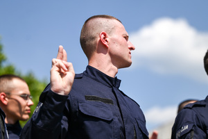 kolorowe zdjęcie przedstawiające policjanta unoszącego prawą dłoń do ślubowania