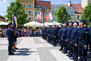 kolorowe zdjęcie przedstawiające policjantów stojących na baczność do sztandaru